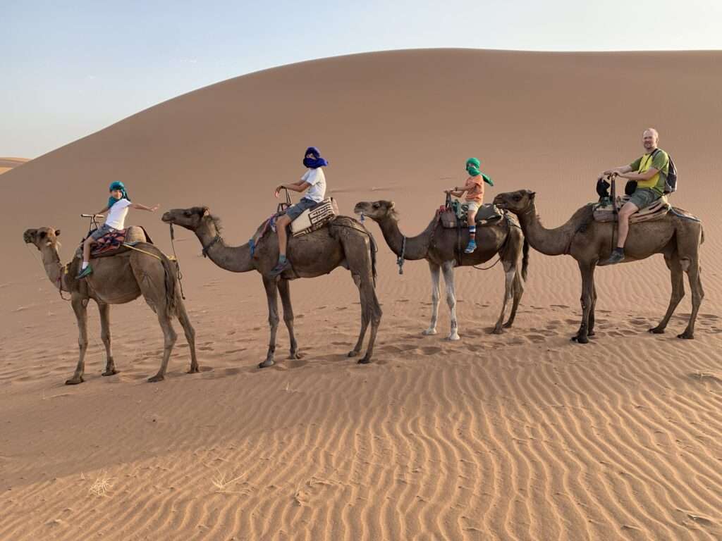 Niños en camello en las dunas de Erg Chigaga en el desierto en Marruecos